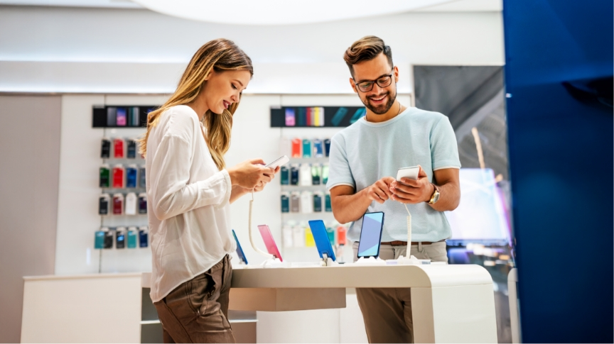 Hombre y mujer revisando teléfonos en tienda de tecnología