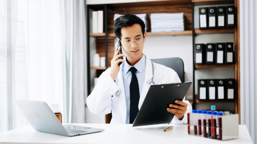 Hombre doctor en oficina hablando por teléfono con portapapeles